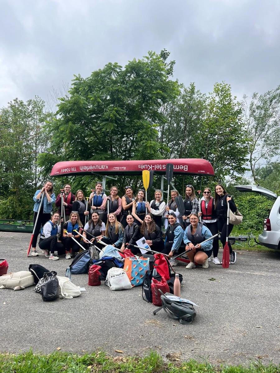 Große Gruppe mit erhobenen Paddeln beim Teamevent